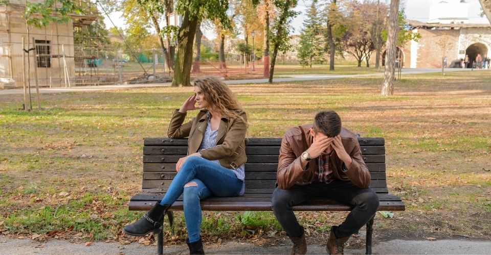 Stel zit op een bankje met afgewende blikken; ze lijken elkaar niet te begrijpen. De afstand tussen hen symboliseert mis communicatie in de relatie.