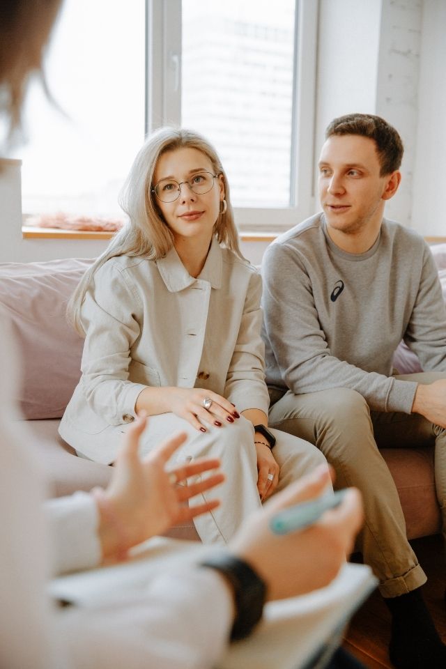 Koppel voert open gesprek met therapeut – professionele en warme setting waarin beide partners zich gehoord voelen.