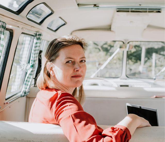 Coach/Therapeut Monique kijkt achterom vanuit een busje – symbool voor een moment van bezinning en keuze voor rust en regie in een druk leven.